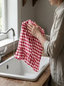 Detailed macro view of red and white checkered ruffle hand towel at a kitchen sink.
