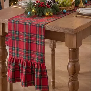 Close-up of red plaid Christmas table runner with ruffled edges on wooden table.