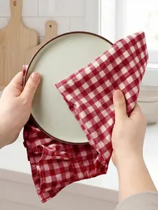 Close-up shot of a red checkered ruffled tea towel being used to wipe a ceramic plate.