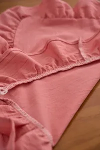 Detailweergave van oudroze katoenen linnen placemat met elegante ruches aan randen