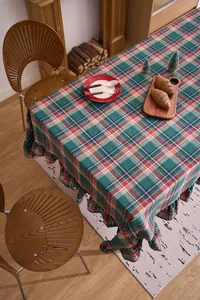 Detail of festive Christmas plaid tablecloth with elegant ruffled edges in a warm room.