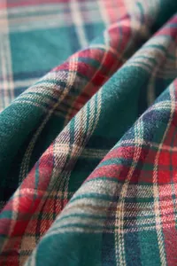 Macro view of Christmas green and red plaid fabric showing woven texture and soft drape detail