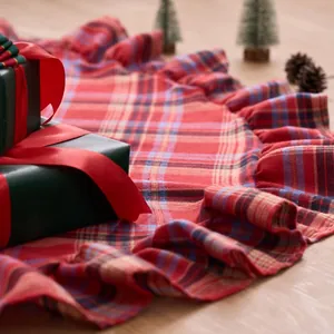 Red plaid ruffled Christmas tree skirt with festive gift box background for holiday decor
