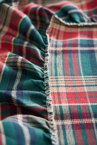 Detailed close-up of Christmas plaid tablecloth with ruffle edge and overlock stitching