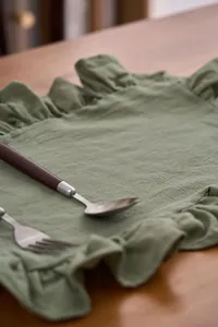 Gedetailleerde close-up van een saliegroene katoenlinnen placemat met ruisranden