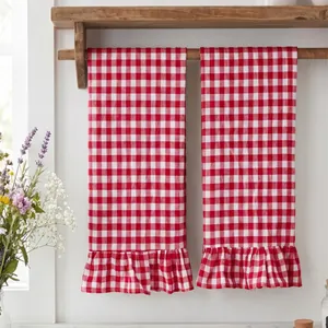 Pair of red and white checkered hand towels with elegant ruffle trim on a wooden rack