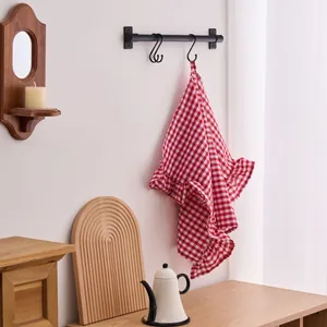 Decorative red and white gingham hand towel with ruffled edges hanging in a cozy kitchen
