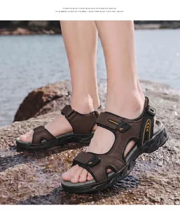 Detail view of men's brown leather outdoor sandals worn on a natural rocky beach