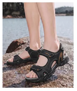 Men's outdoor leather sandals featuring non-slip soles and adjustable straps on rocky beach.