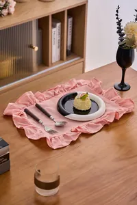 Detailopname van de textuur van de roze placemat met ruches op een houten tafel
