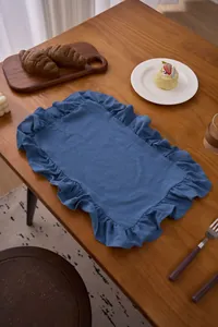 Blauwe katoenen linnen placemat met ruches op een houten tafel voor tafeldecoratie.