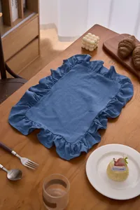 Blauwe katoen-linnen placemat met ruches op houten eettafel