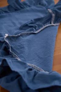 Detailweergave van effen blauwe katoenen placemat met elegante ruches.