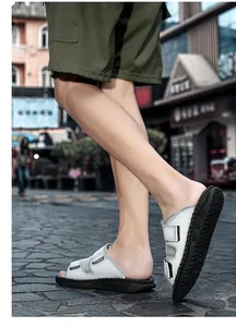 Detail shot of stylish silver men's Velcro sandals worn on a cobblestone street in daylight