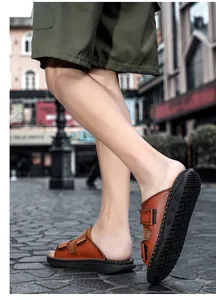 Stylish brown casual men's slippers with velcro straps on model feet walking outdoor.