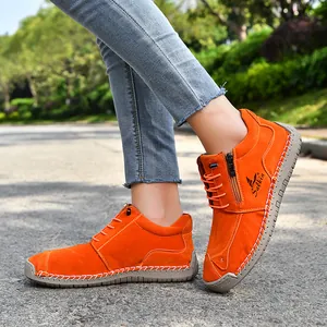Detail shot of orange hand-stitched casual shoes with side zipper and soft sole.