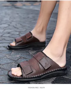 Close-up of brown casual sandals with adjustable Velcro straps on a stone walkway