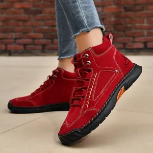 Detailed side view of red men's ankle boots featuring decorative hand-stitched seams.