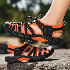 Outdoor sports beach sandals with orange and black elastic straps shown on rocky ground