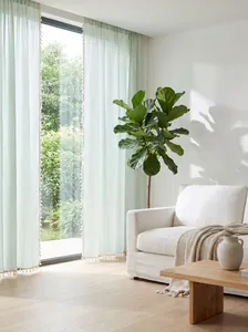 Detail of light green striped sheer curtains featuring delicate tassel fringe decoration.