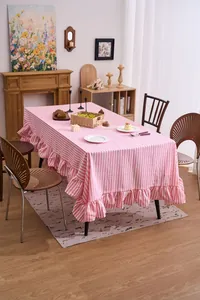Detail view of a pink and white striped tablecloth featuring elegant ruffled edges
