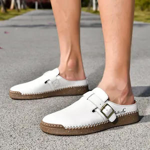 Detailed view of white leather clogs with buckle strap on feet in outdoor setting