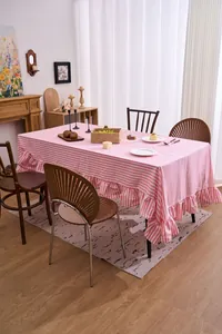 Pink and white striped tablecloth with elegant ruffled trim on a wooden table.