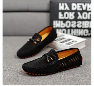Vista detallada de mocasines negros perforados con suelas de goma color naranja