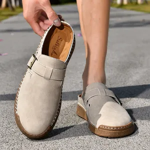 Detailed view of beige suede loafers featuring decorative buckles and white stitching