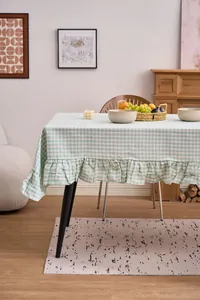 Detalle de mantel a cuadros verdes estilo retro con volantes en un ambiente hogareño.
