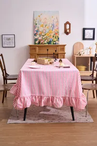 Pink and white striped tablecloth with ruffled edges on a cozy wooden dining table