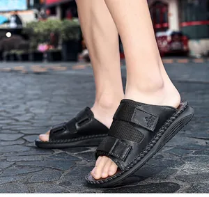Detail view of black casual slides with adjustable hook and loop straps on cobblestones