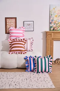 Decorative striped velvet throw pillows with ruffled edges displayed on a white sofa.