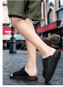 Detail view of black casual sandals with adjustable velcro straps on a city street.