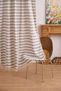 Light French striped semi-sheer curtain with elegant tassel trim in a cozy home interior