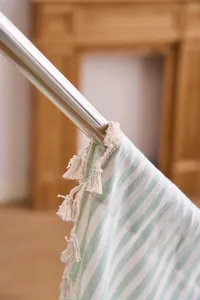 Detail of French style green striped curtain with elegant beige tassel fringe decoration