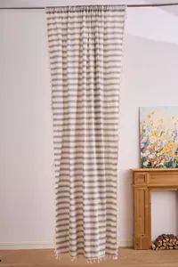 Detail of a light-filtering French striped curtain with elegant tassel trim in a home setting.