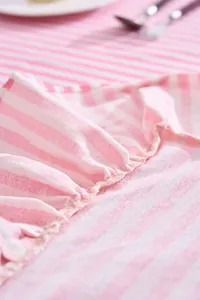 Detail view of pink and white striped tablecloth with delicate ruffled edges.