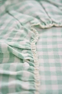 Detalle de primer plano del borde con volantes de un mantel vintage de cuadros verde