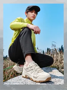 Detailed view of cream-colored outdoor hiking shoes worn by male model on rocky terrain.