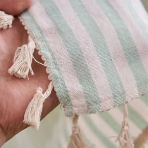 Detailed macro view of light green and white striped linen curtain with elegant tassels