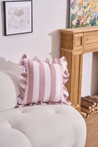 Pink and white wide striped pillowcase with elegant ruffled edges shown on a white sofa