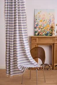 Close-up detail of navy blue striped curtain with delicate fringe tassels in home setting