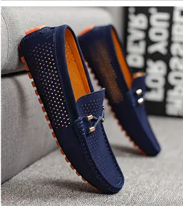 Vista detallada de mocasines de ante azul marino con perforaciones transpirables y suelas naranjas