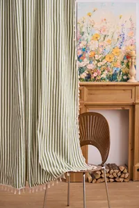 Detalle de cortina a rayas verdes de estilo francés con borlas blancas decorativas.