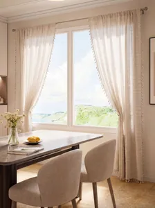 Dettaglio di tenda color crema con nappe e strisce boho in una sala da pranzo