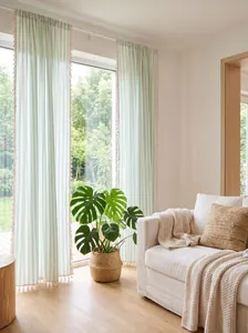 Detail view of light green striped linen curtain with decorative tassels in a sunny room context