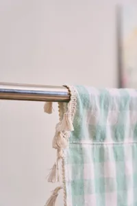 Detailed macro view of sage green gingham cotton linen curtain with handmade tassels