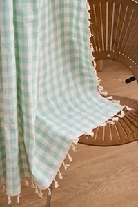Macro detail of sage green gingham cotton-linen curtain with handmade tassel trim