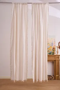 Coppia di tende in cotone e lino a righe crema con bordi a nappa in ambiente caldo